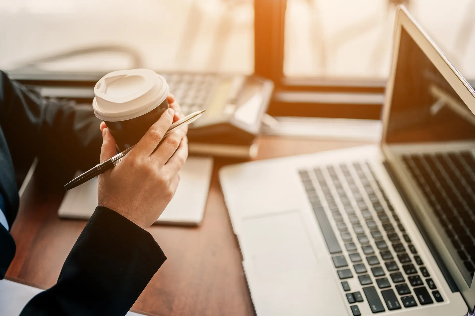 Close-up hand Business women drink hot coffee between working. laptop, calculator and paper on the t
